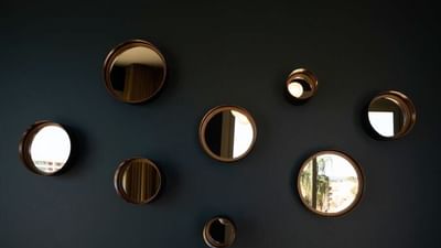 Seven round mirrors of varying sizes are mounted on a dark blue wall.