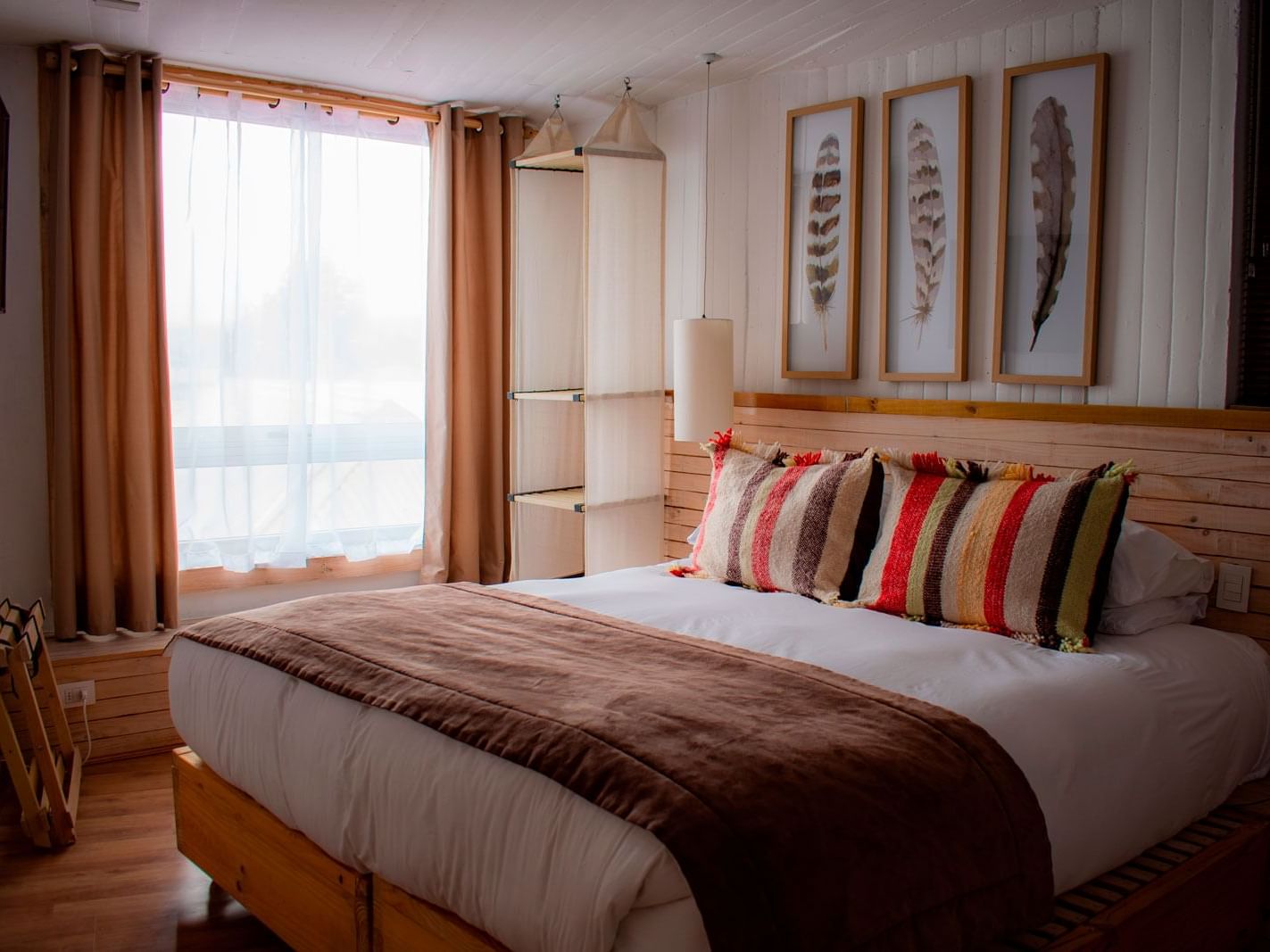 Quarto Deluxe com cama grande, manta marrom e almofadas listradas coloridas no NOI Indigo Patagonia