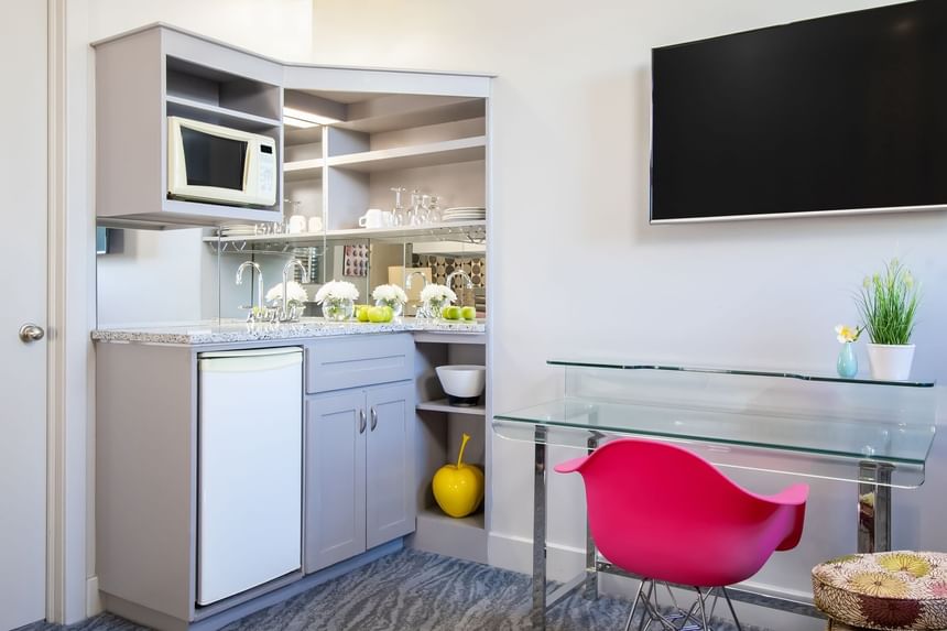 TV, work desk & kitchenette with fresh flowers, glassware & amenities in Queen Premiere Blast at Retro Suites Hotel