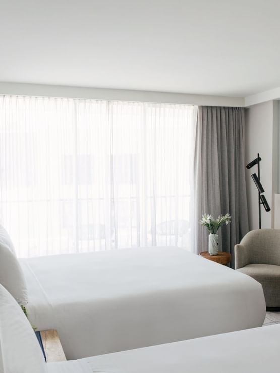 Atrium Twin at Elysium Manly with a grey armchair by a wooden bench under framed art near floor-to-ceiling sheer curtains