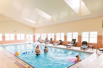 Family swimming in the indoor pool with lounge chairs in Rodd Crowbush Golf & Beach Resort, the best resorts in PEI, Canada