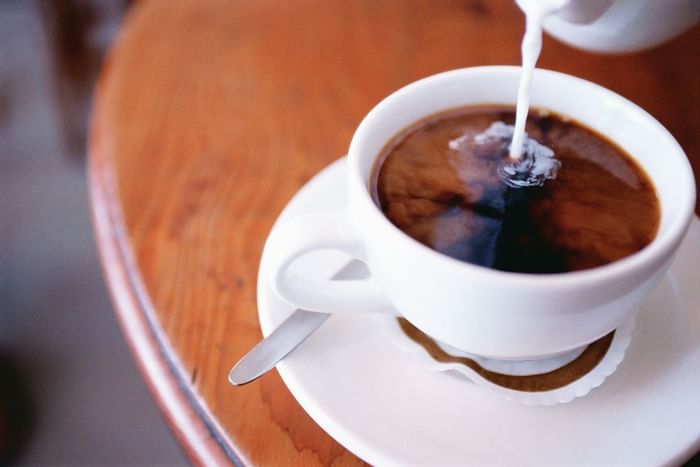 Pouring creamer in coffee