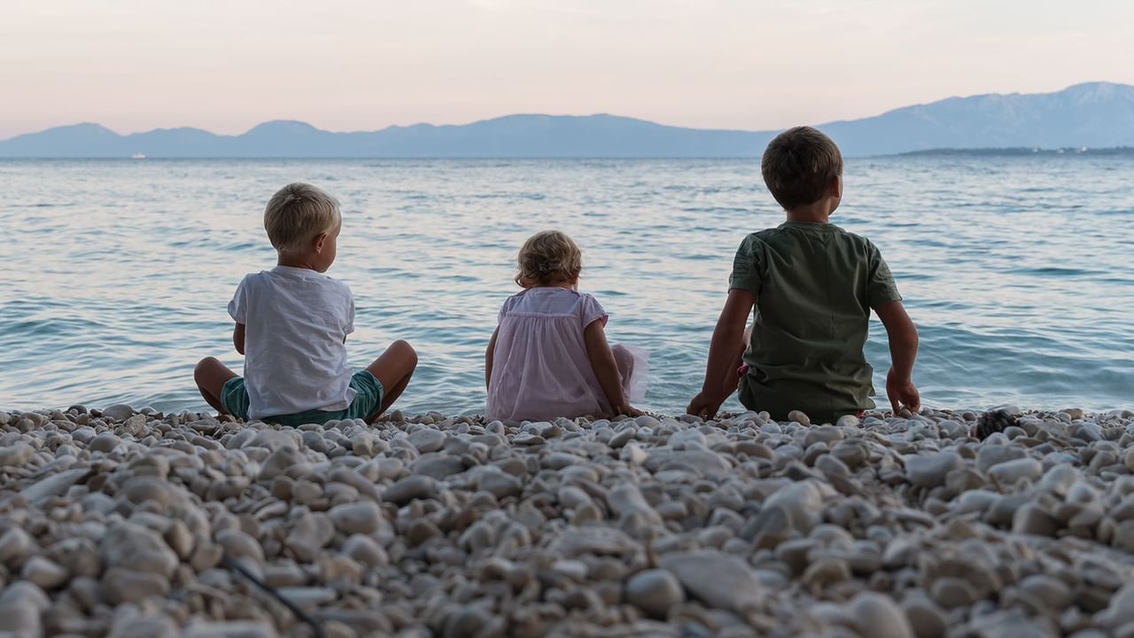 three kids sitting on a beach