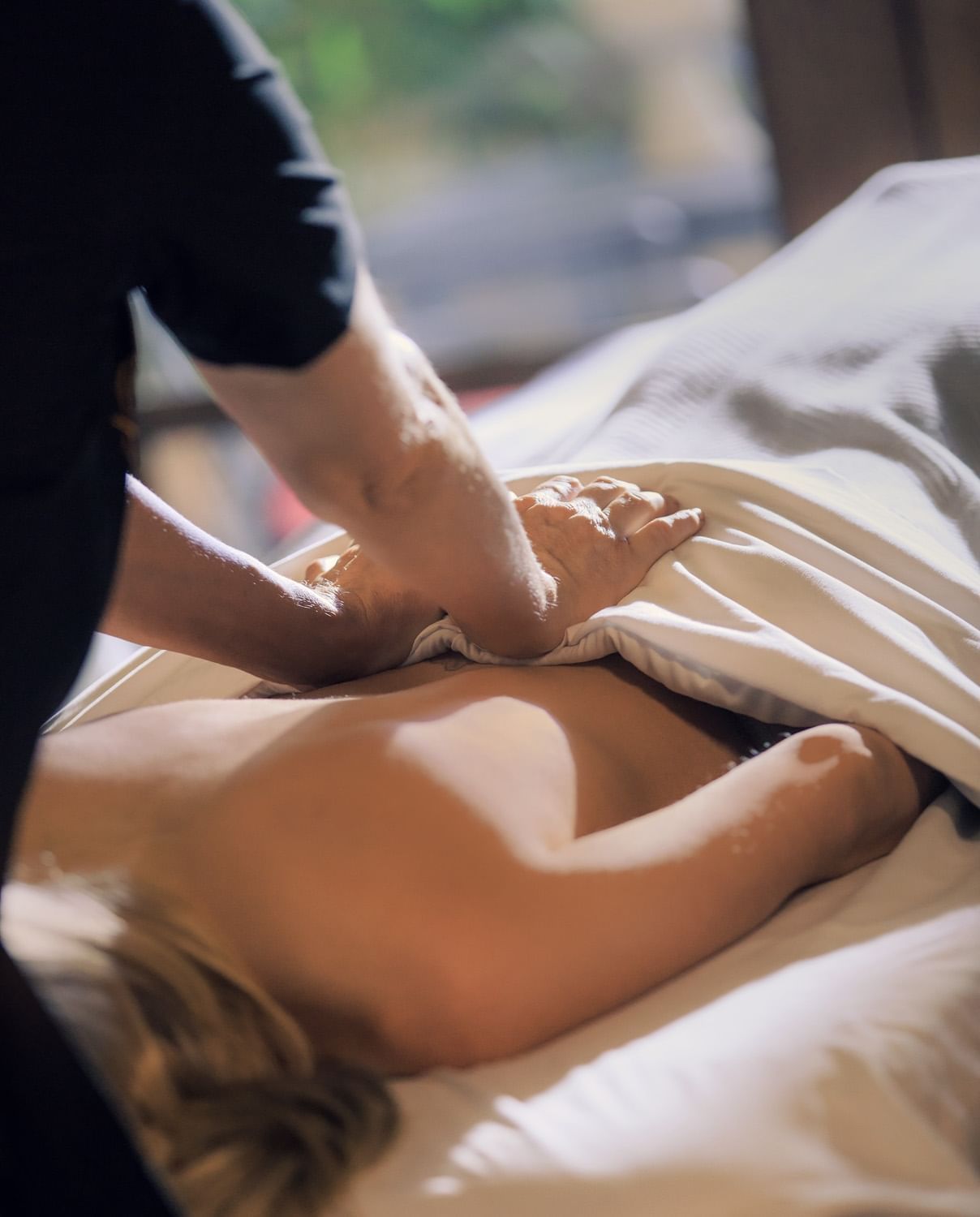 Woman laying face down on massage table while being massaged.