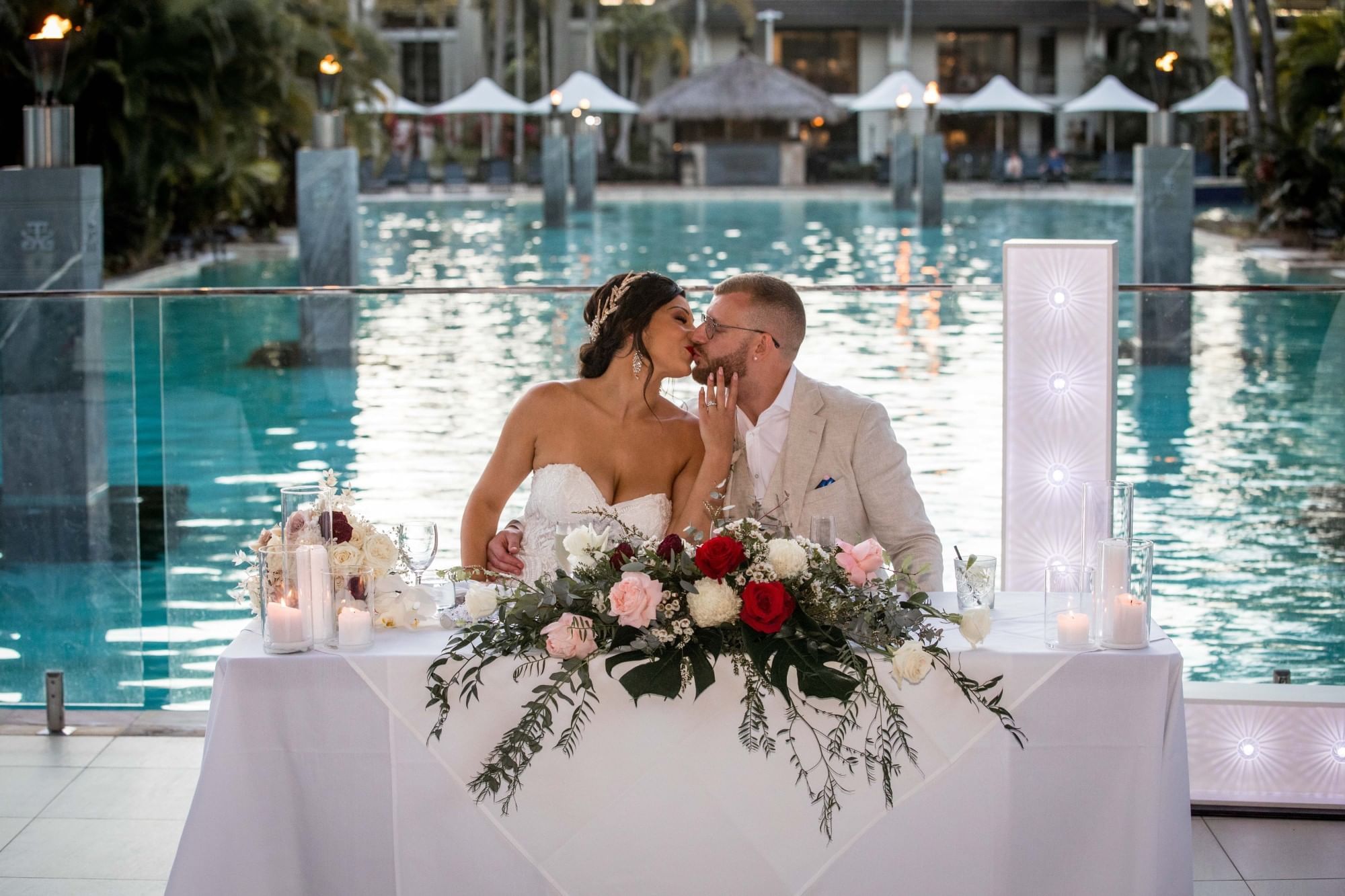 Bride & groom kissing by the pool in Four Mile Beach at Pullman Port Douglas Sea Temple Resort & Spa