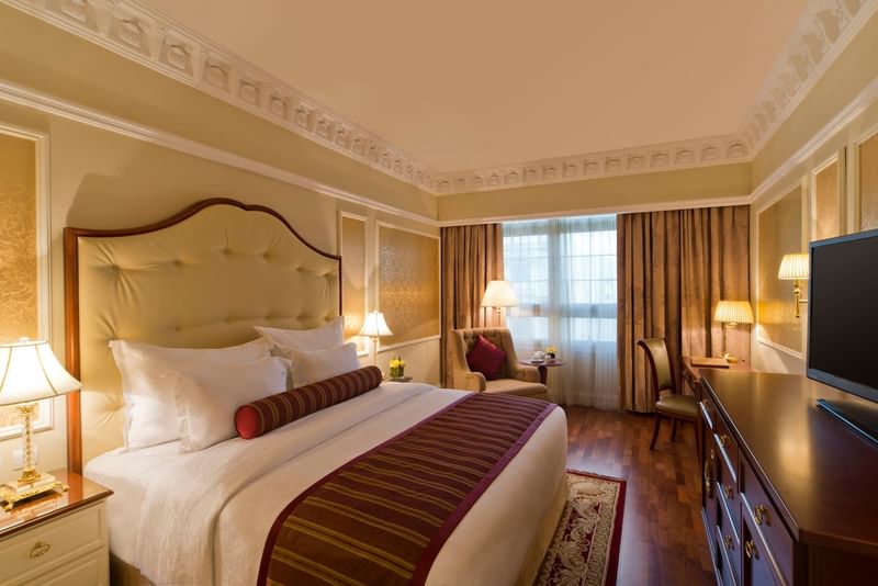 غرفة نوم فاخرة بسرير مزدوج وأثاث خشبي كلاسيكي وإضاءة دافئة في Warwick Doha