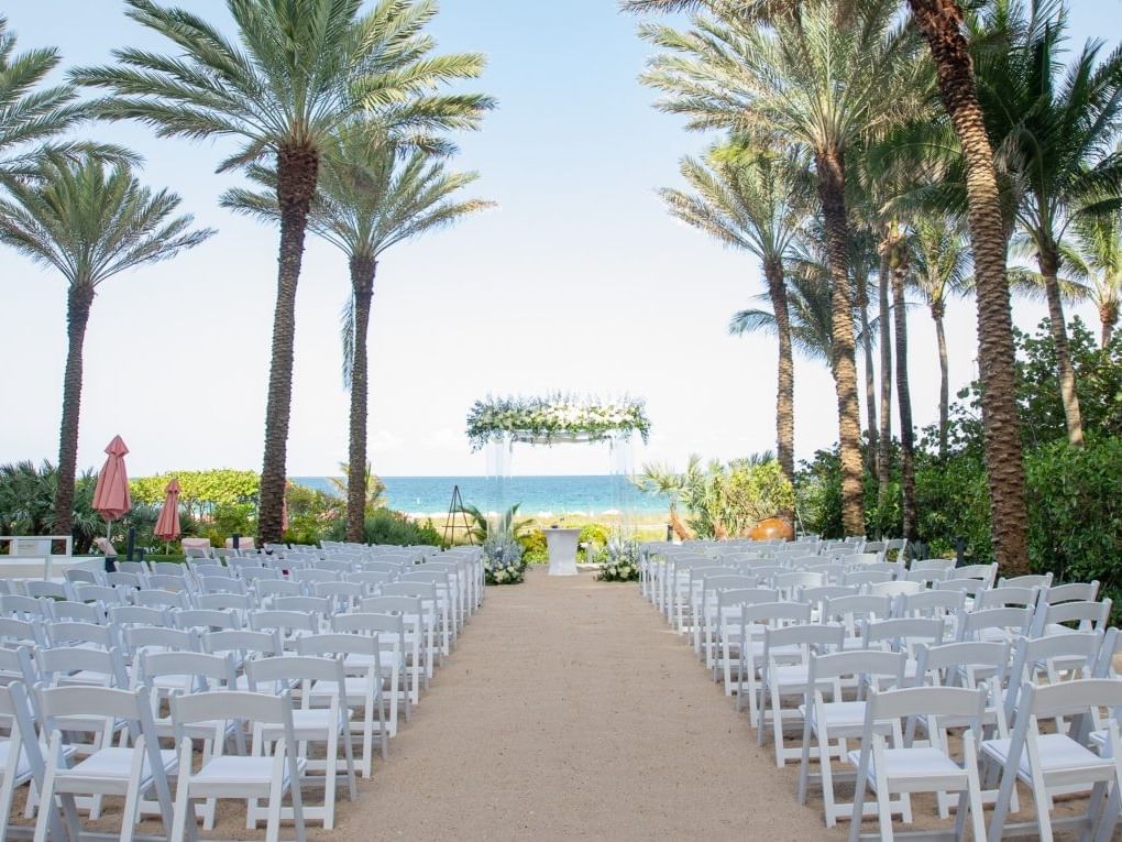 Des rangées de chaises disposées le long d'une allée menant à une arche fleurie au Grand Beach Hotels, offrant un cadre idéal pour les événements à Sheffield