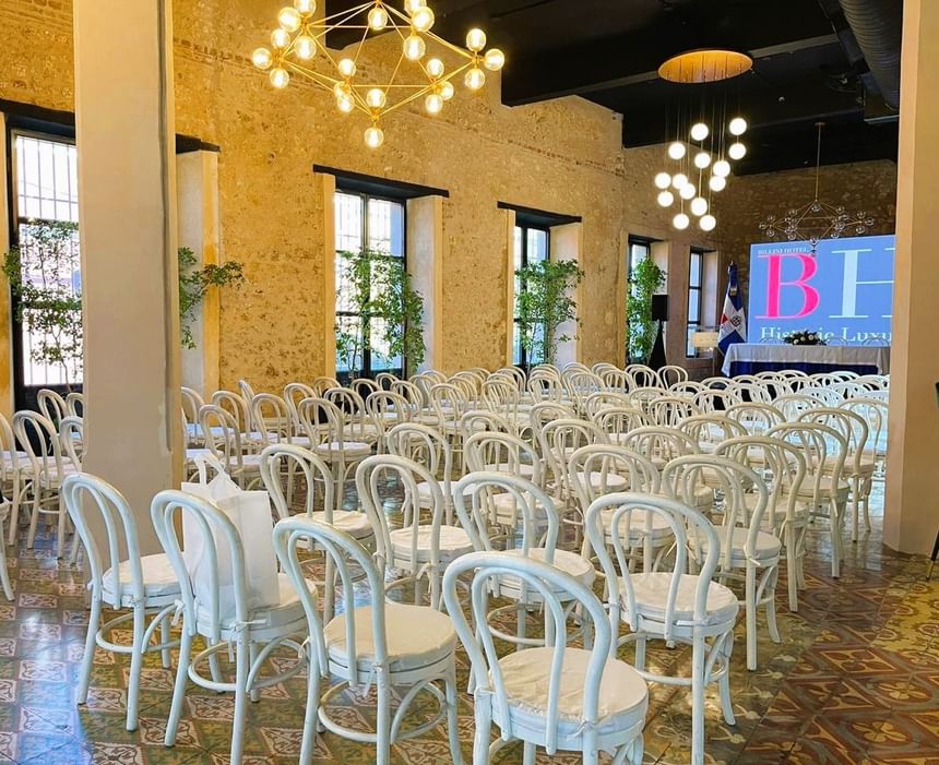 Casa Mia with wooden chairs by floral tables under hanging ferns and glass at Billini Hotel Historic Luxury