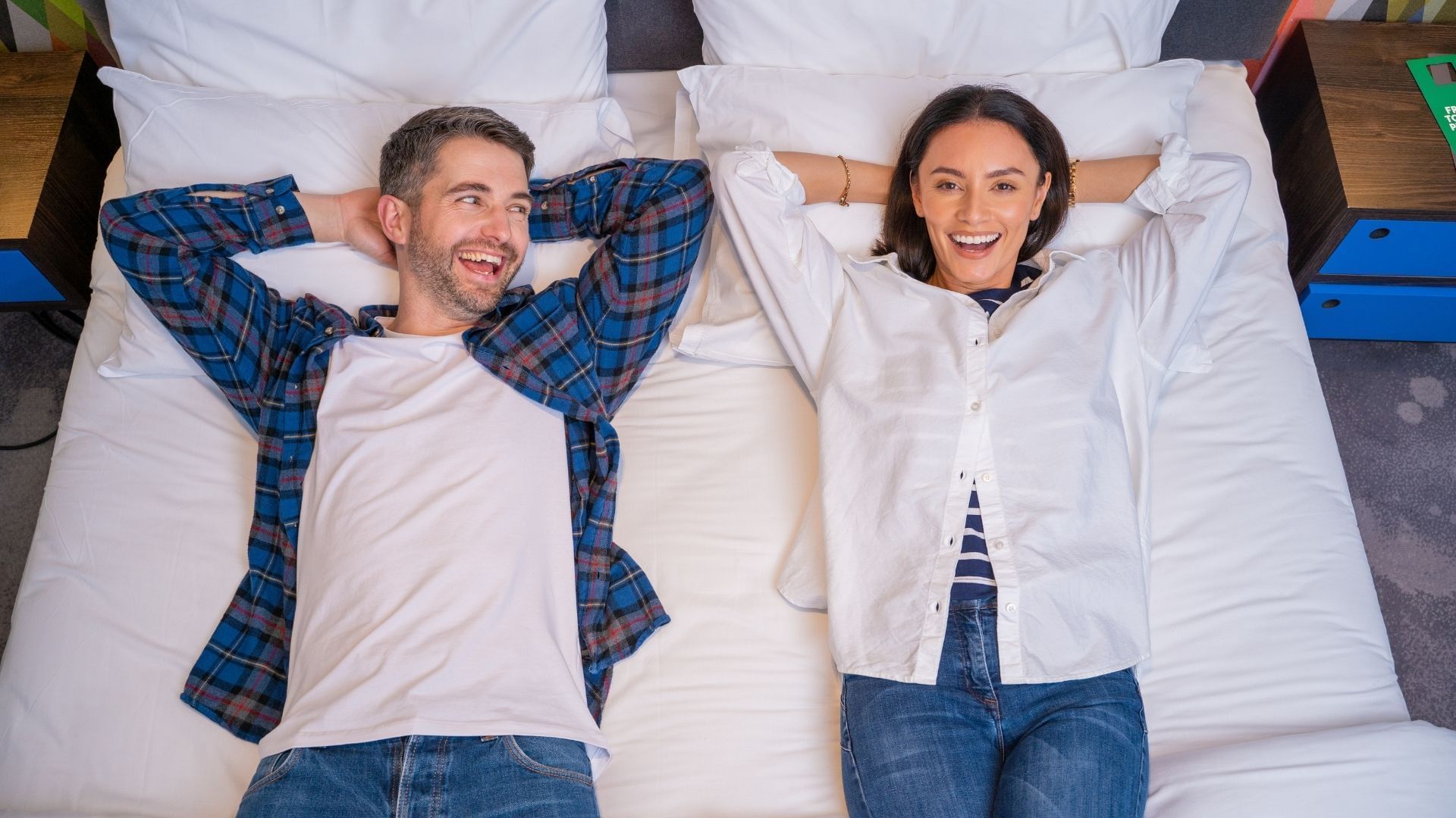 A couple lying down on a bed at Village Hotels
