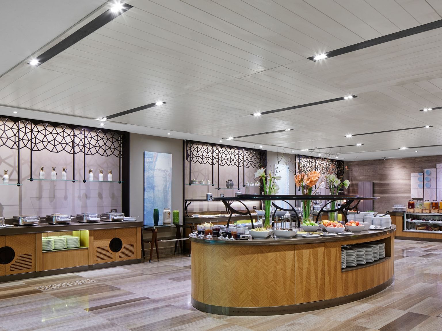 Modernes Buffetrestaurant mit Holztischen, stilvollen Speisen, Blumenarrangements und heller Beleuchtung – Titanic Chaussee Berlin.