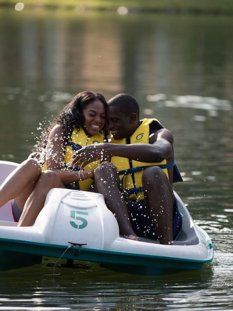 Couple having a laugh while enjoying the pedal boat ride on the Lake near Cove Pocono Resorts