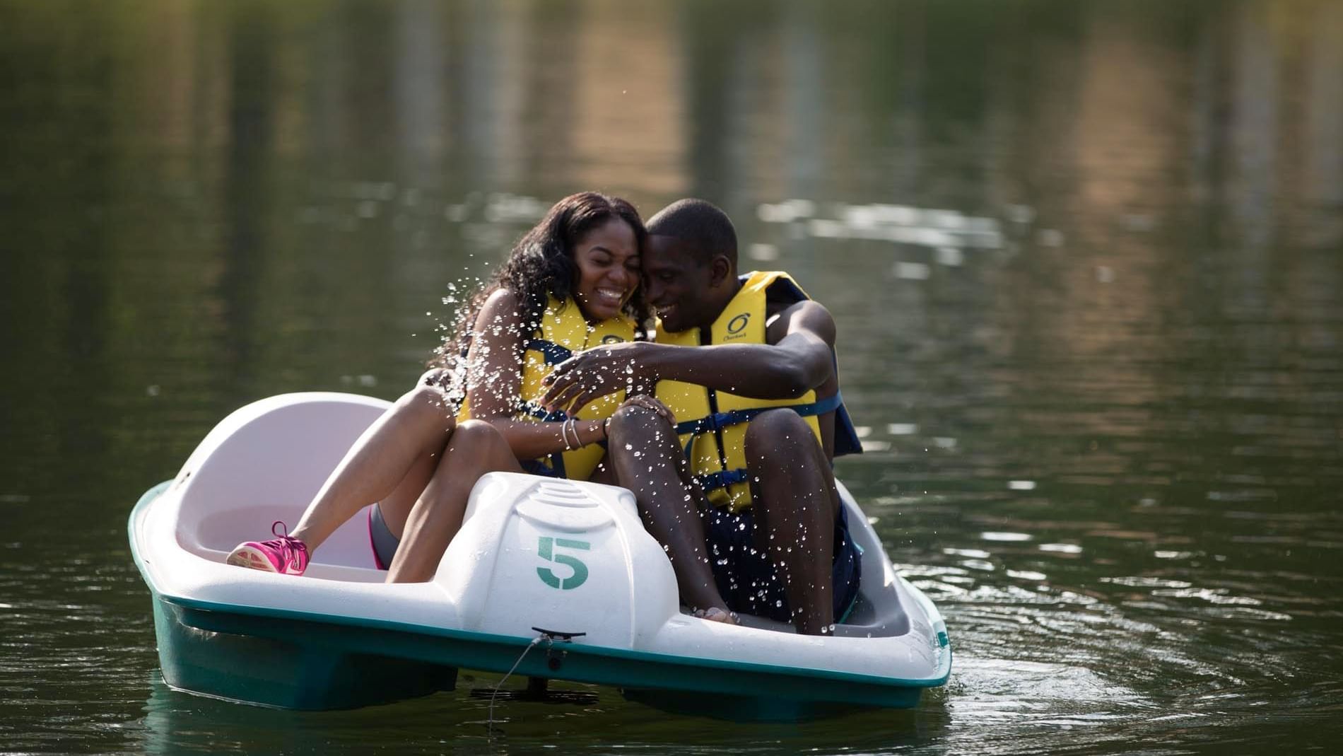 Couple having a laugh while enjoying the pedal boat ride on the Lake near Cove Pocono Resorts