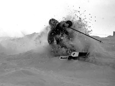 Skier carving through deep snow with skis and poles at Elevation Resort Spa