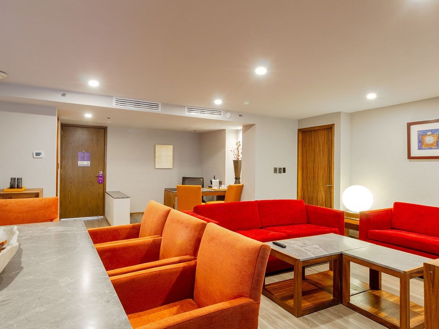 Salón de la Master Suite King con sofás rojos y sillas naranjas en el Camino Real Aeropuerto México en Ciudad de México
