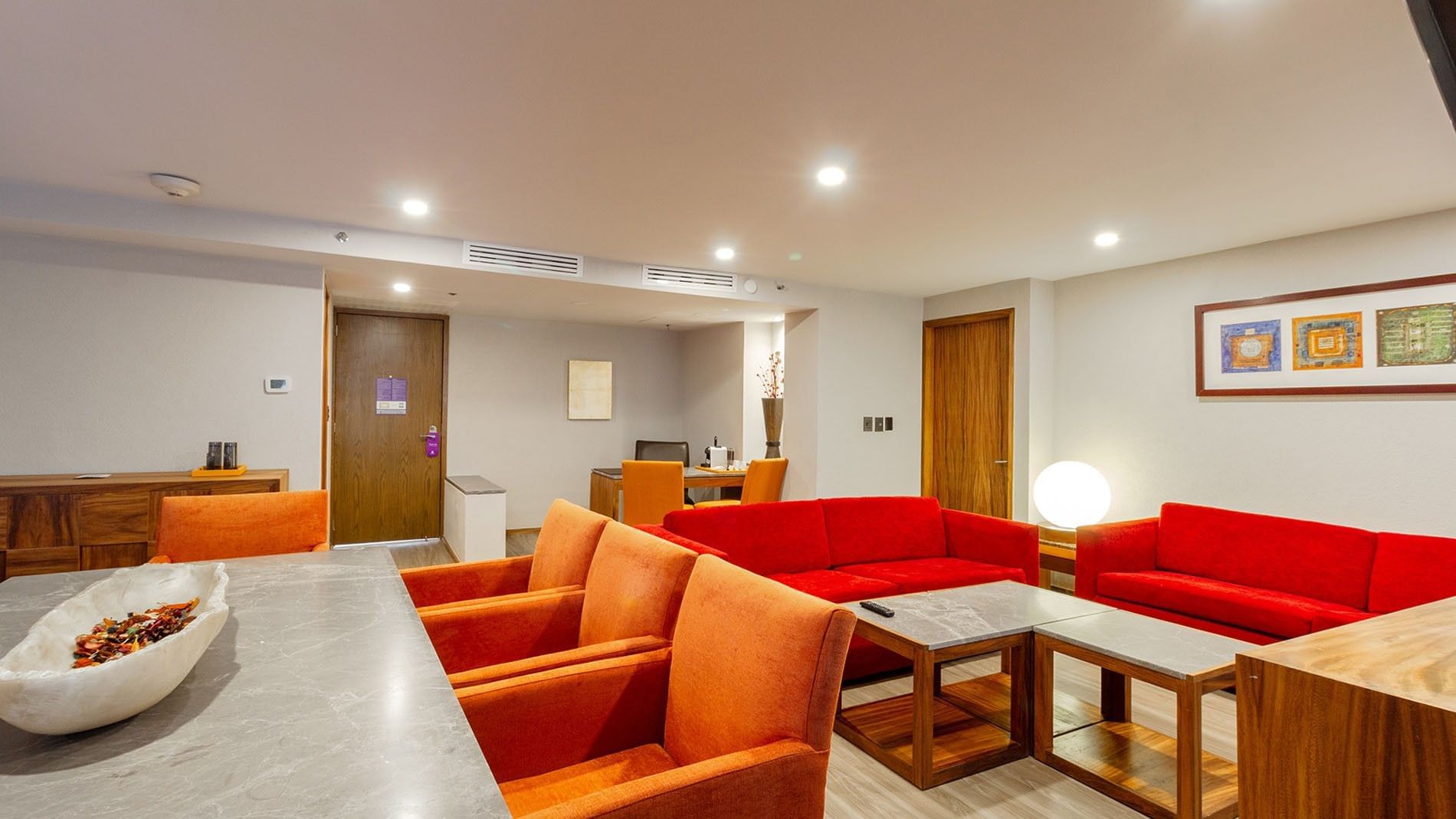 Salón de la Master Suite King con sofás rojos y sillas naranjas en el Camino Real Aeropuerto México en Ciudad de México