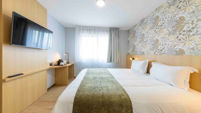 Room with bed, flat screen TV, and desk at The Originals City Hotel du Parc Gravelines.