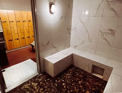 Tiled steam room seating with stone floor adjacent to locker area in Moon Spa at La Tourelle Hotel and Spa