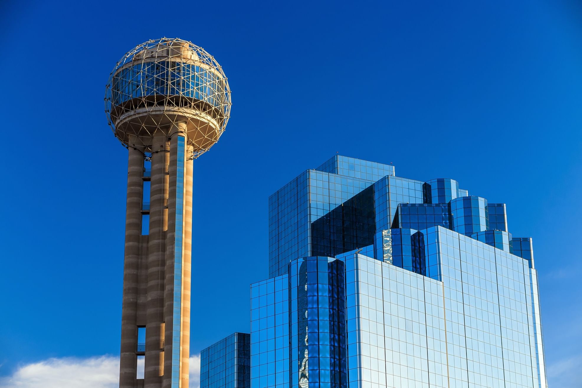 Tall glass skyscraper and sphere-topped tower under blue sky near Warwick Corporate