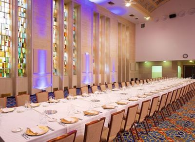 A long banquet table is set for a formal event in the Osgood Building grand ballroom at the Bolger Center