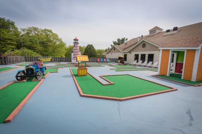 Fox Ridge Resort colorful outdoor mini golf course with obstacles, a lighthouse, and a house with white and orange walls.