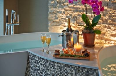 glass of wine and food by two bath tubs