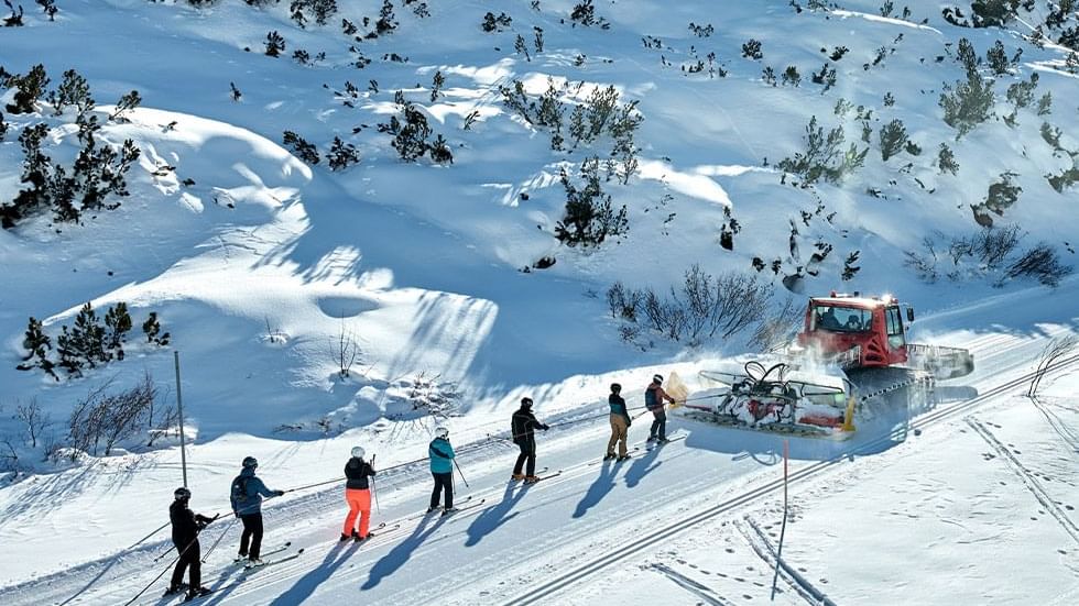 Skiers following a snowcat on a snowy hillside with trees near Falkensteiner Hotel Montafon