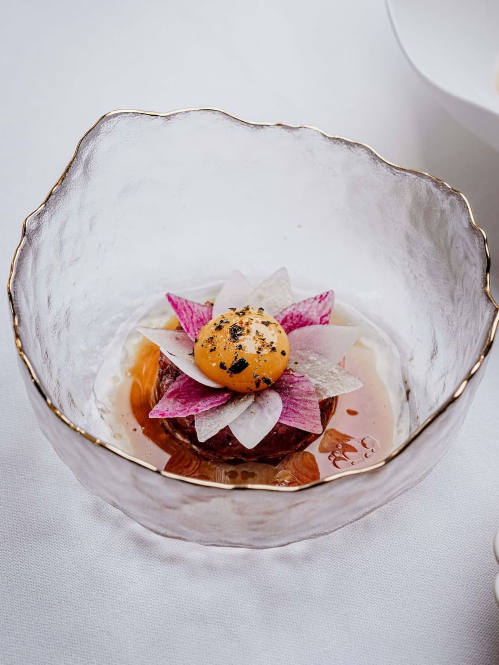 Gourmet food arrangement featuring a yolk flower placed on dark protein at The Capital Hotel, Apartments and Townhouse