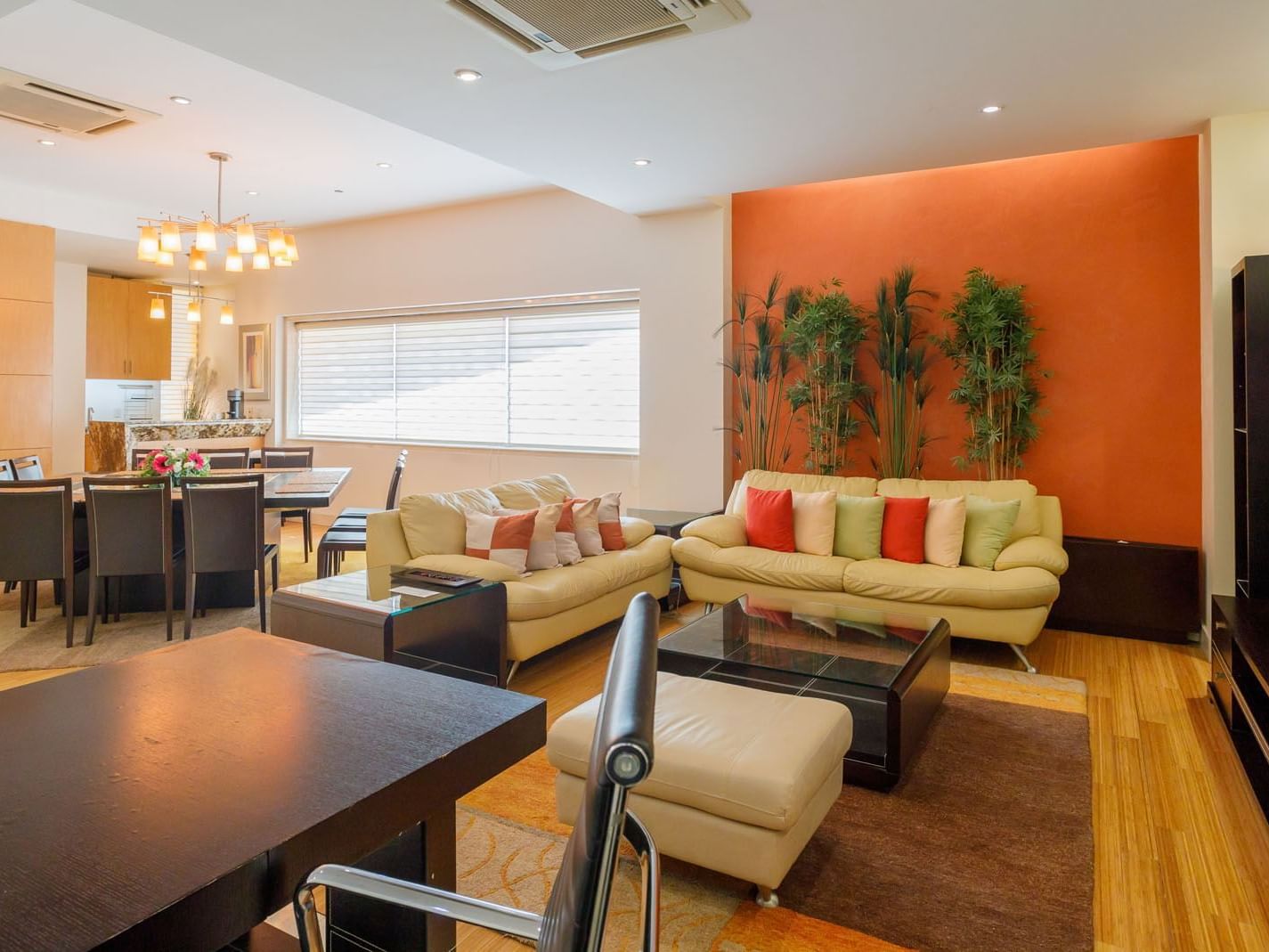 King Presidential Suite living area with a bright orange accent wall, cream sofas, and a dining set at Real Inn Torreon