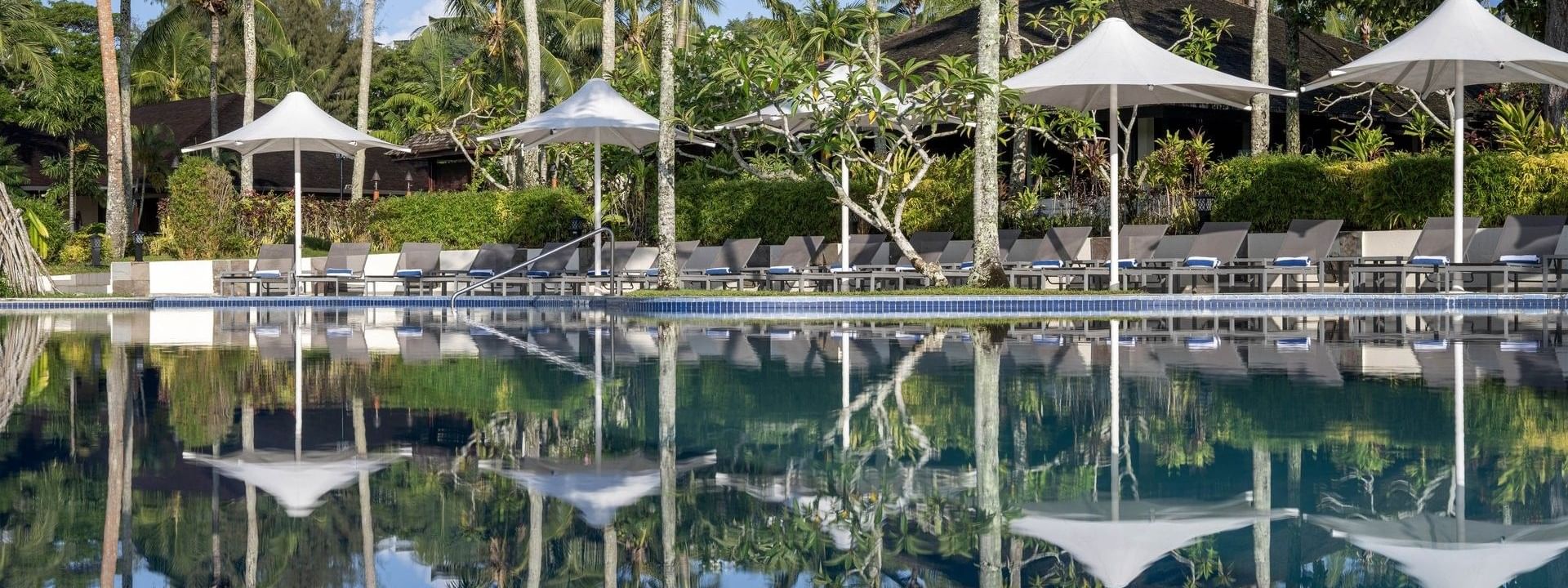 Tropical pool and terrace beach area with loungers under umbrellas at Warwick Le Lagon in Efate