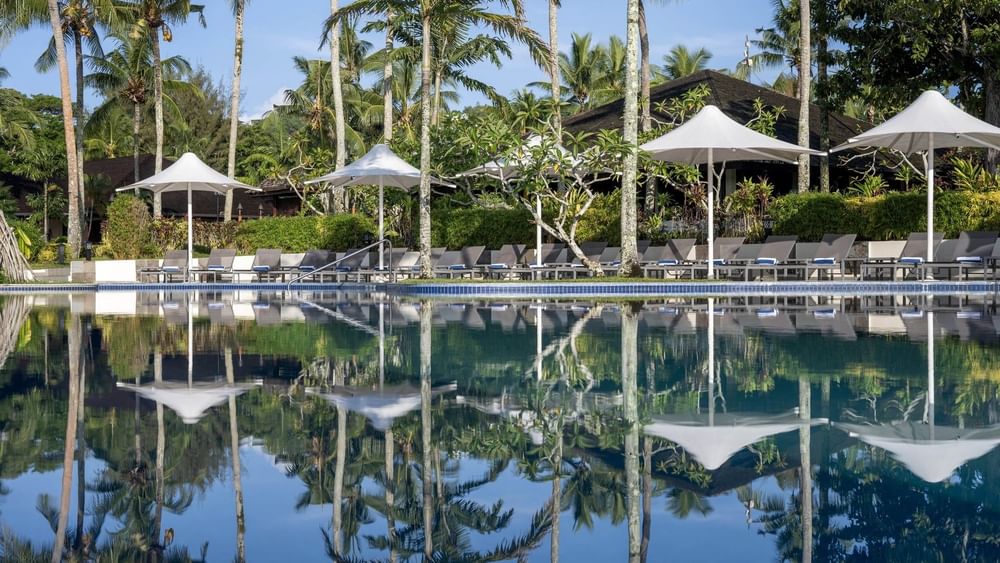 Tropical pool and terrace beach area with loungers under umbrellas at Warwick Le Lagon in Efate.