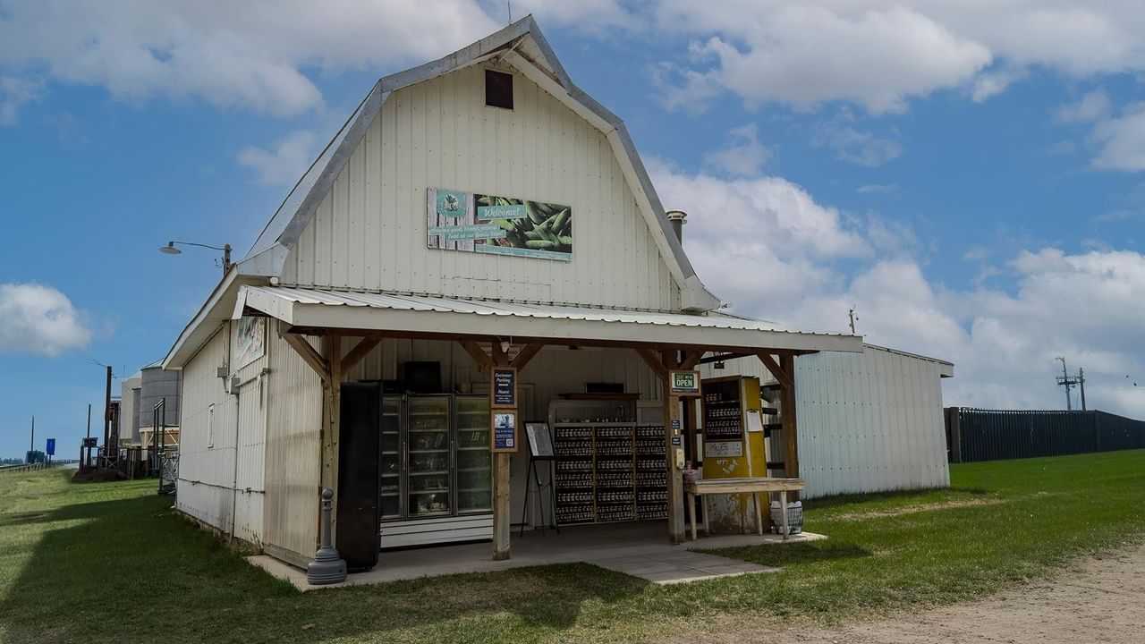 White barn with Edgar Farms sign and open porch on green field.