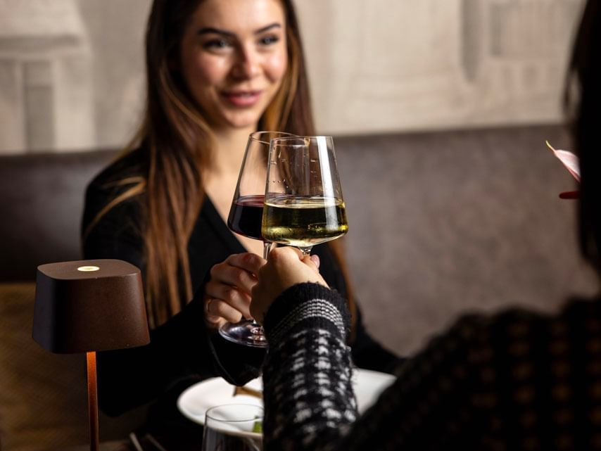 Two women clinking wine glasses in a restaurant at EMME Restaurant