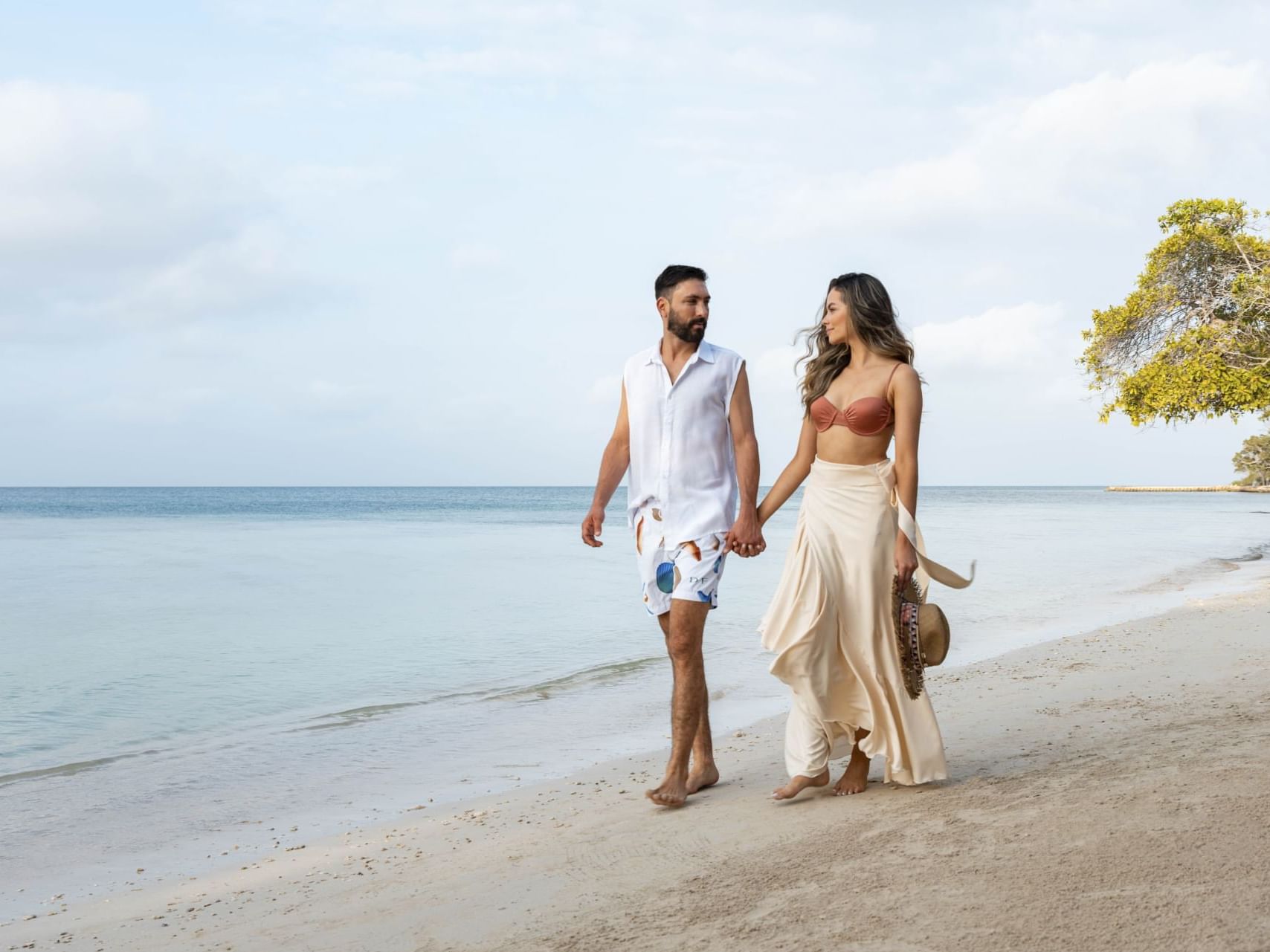 A couple walking on a beach while holding hand near Hotel Isla Del Encanto