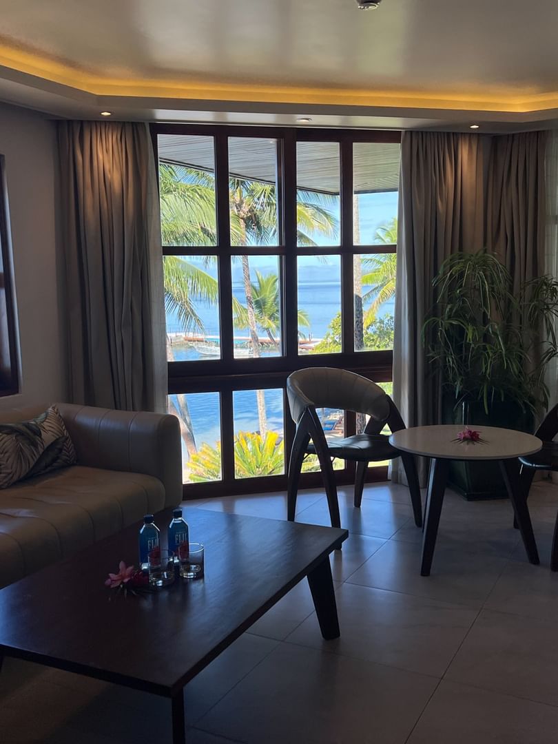 Suite with couch, table, chairs, and ocean view at Warwick Fiji Resort and Spa in Korolevu.