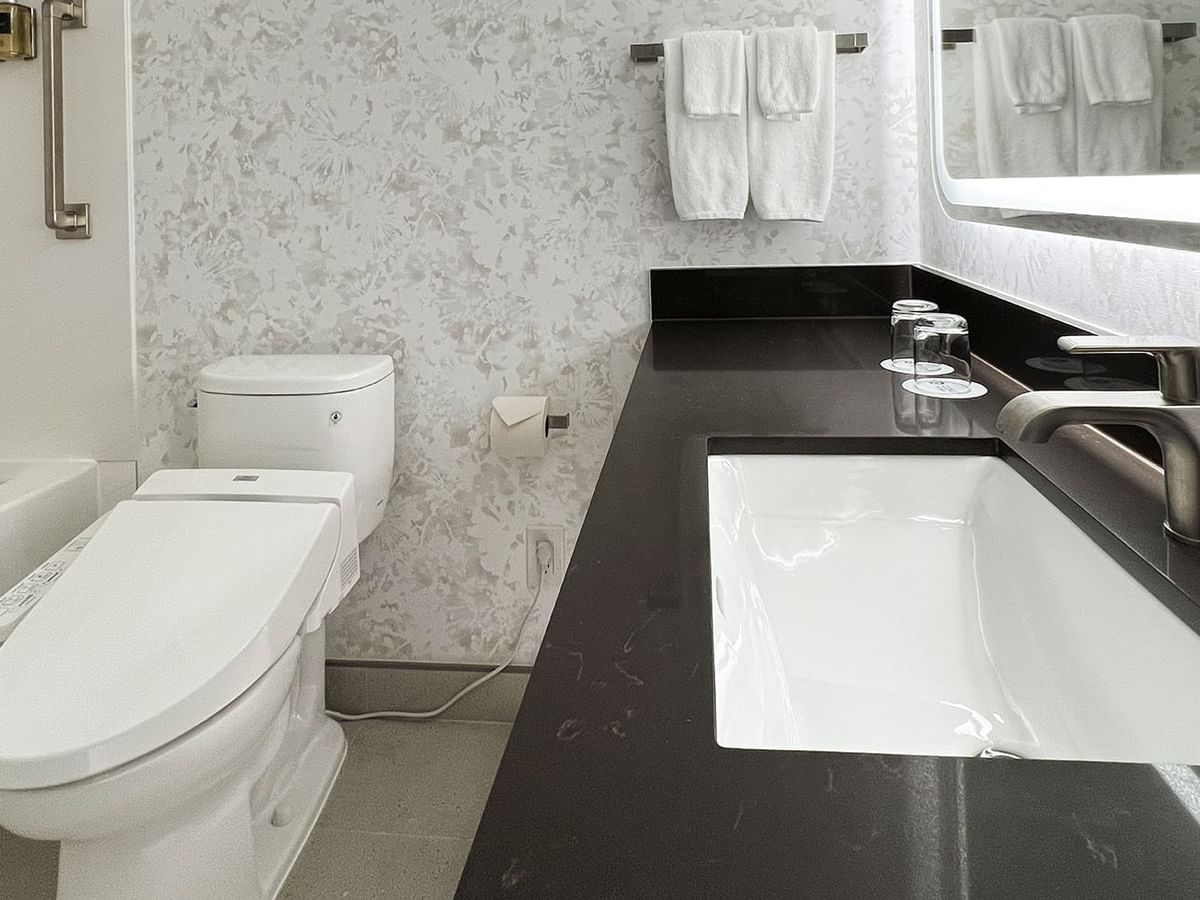 Hotel washroom with TOTO washlet, bathtub, sink, soap, towels and mirror