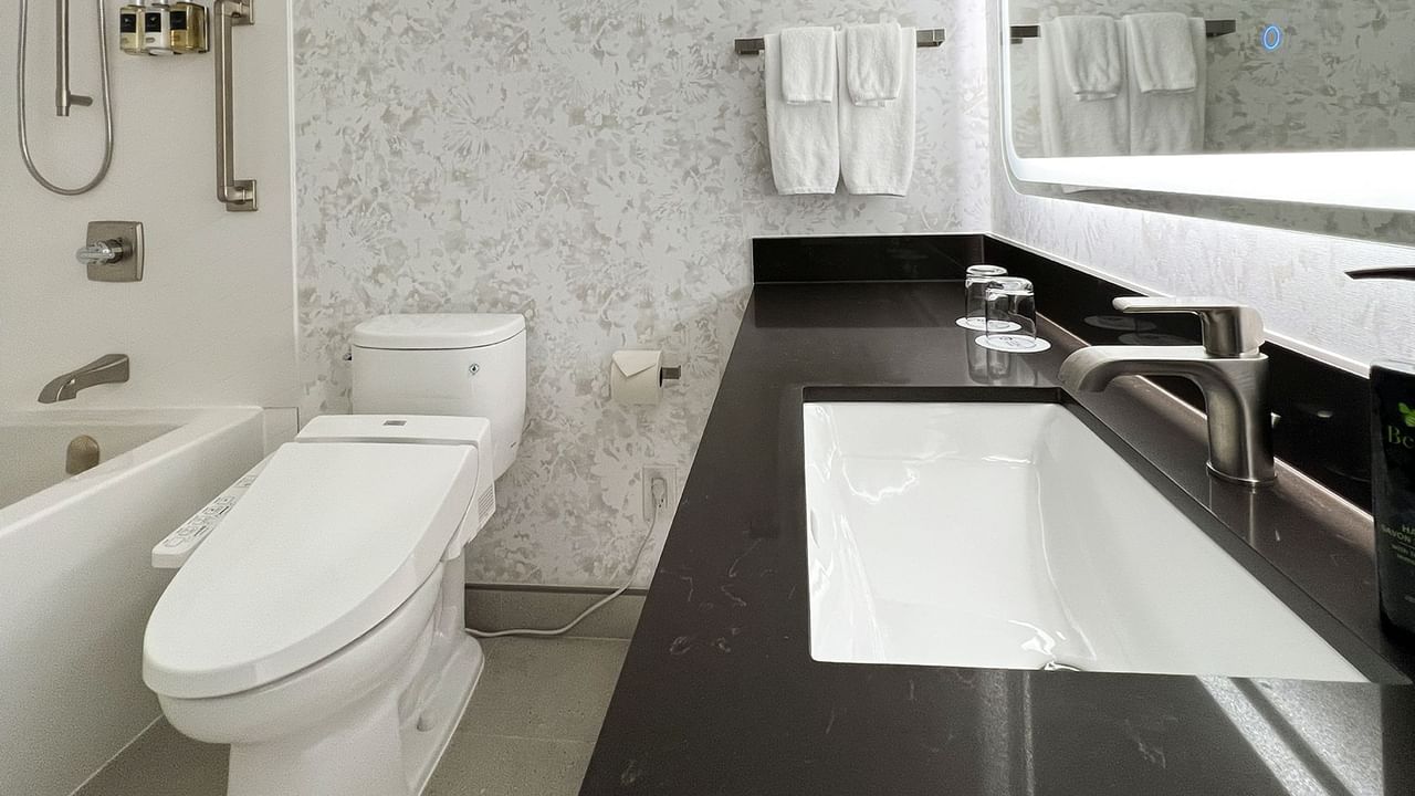 Hotel washroom with TOTO washlet, bathtub, sink, soap, towels and mirror