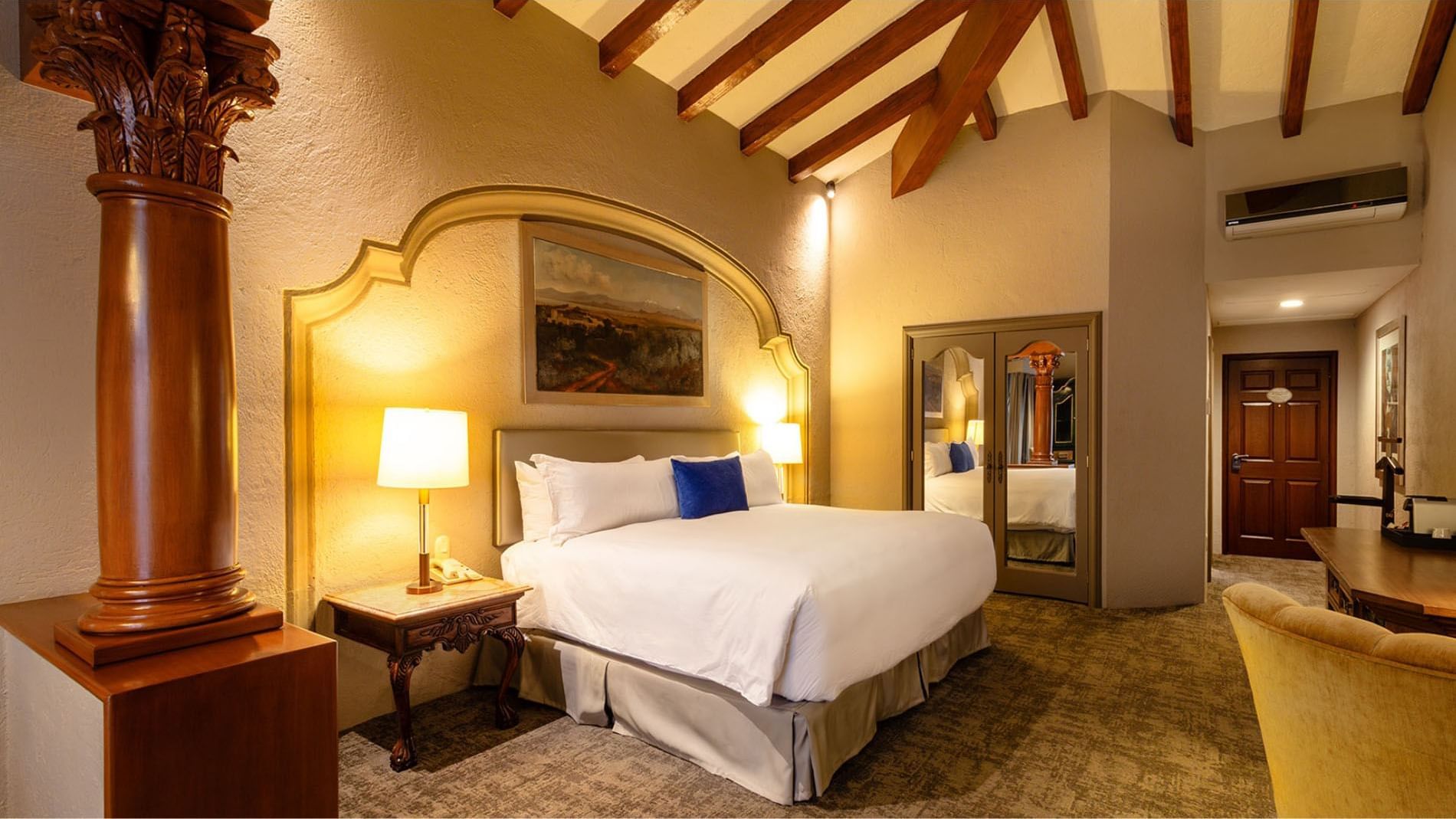 King Grand Class with exposed ceiling beams and a large painting over the bed at the Quinta Real Guadalajara