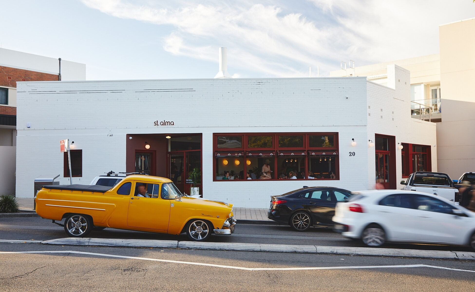 St Alma at Elysium Hotels is a Mexican restaurant in a white building with red window frames and a yellow classic car