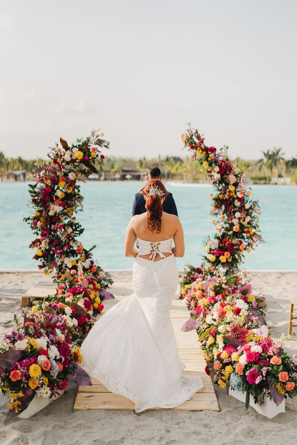 Couple by the floral wedding arch at Playa Blanca Beach Resort