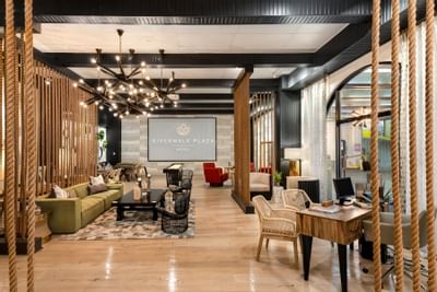 Lounge with rope dividers, stylish furniture, and large signage at The Riverwalk Plaza Hotel