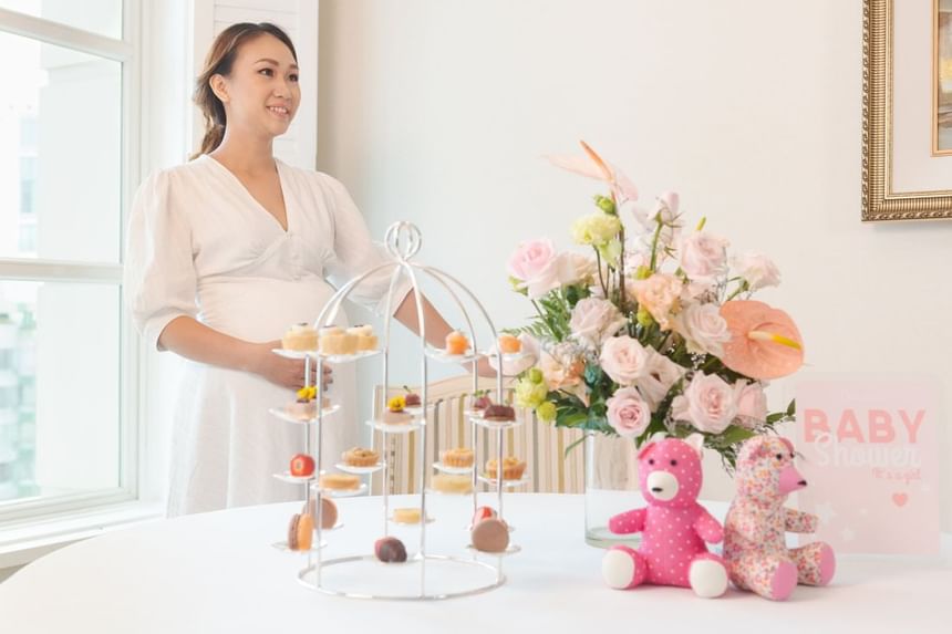 Baby shower table setup with a tiered dessert stand, flower arrangements, and two plush teddy bears at Park Hyatt Saigon