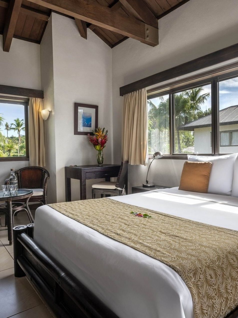 Large bed and small side dark wood seating with window view in Lagoon View Room Queen at warwick le lagon-vanuatu