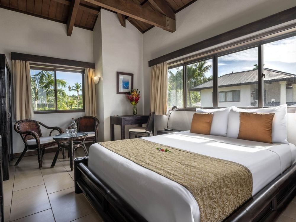 Large bed and small side dark wood seating with window view in Lagoon View Room Queen at warwick le lagon-vanuatu