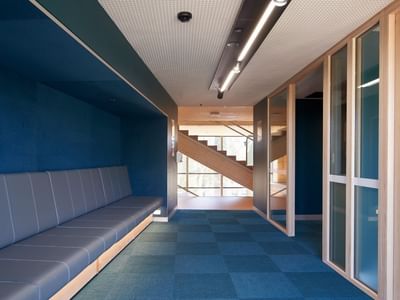 Blue and wooden interior hallway with bench and glass doors at La Trobe University.