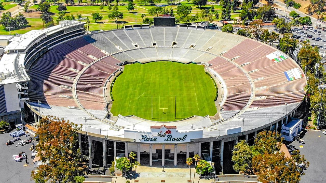 Aerial view of Rose Bowl stadium with a green field and surrounding empty seating.