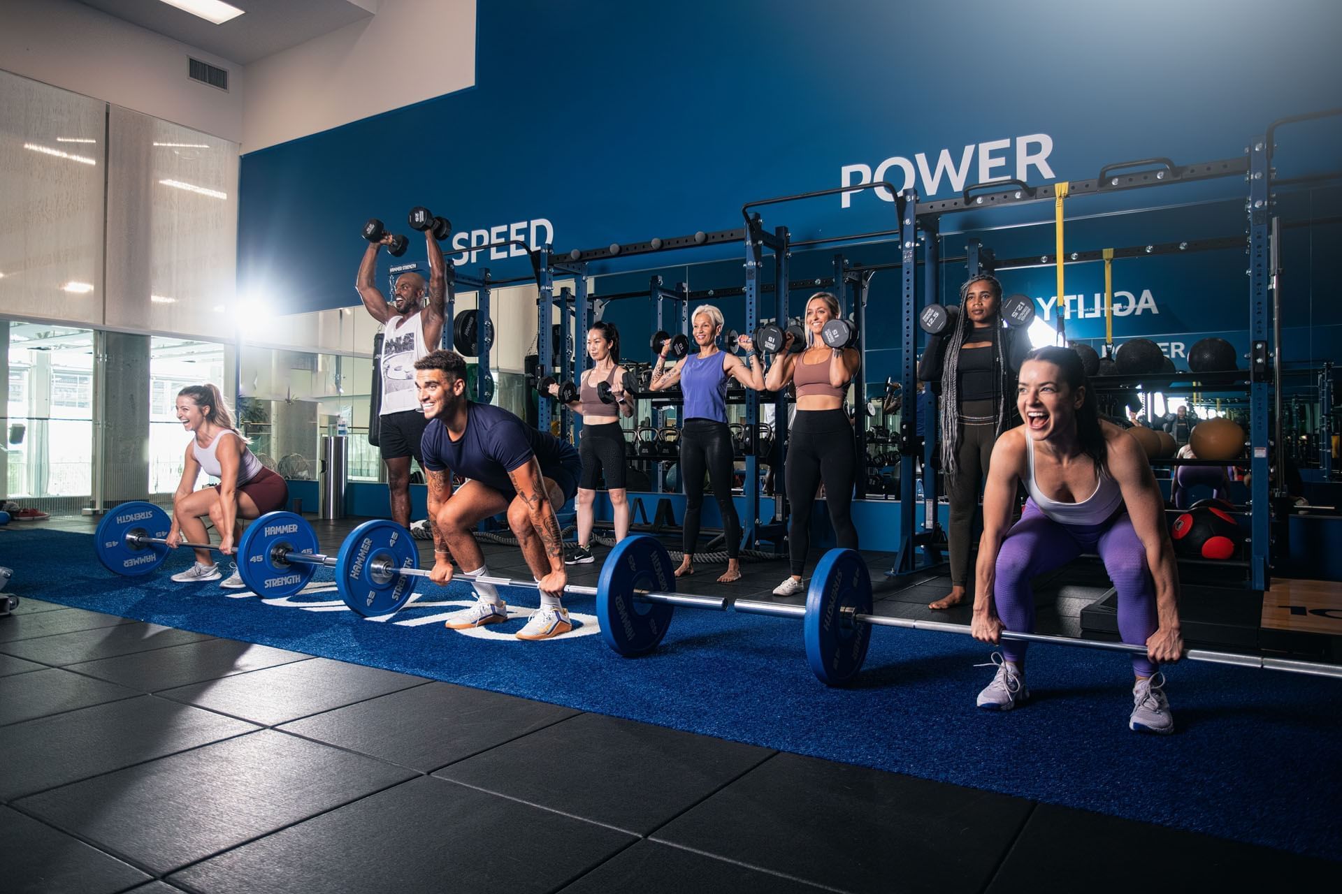 Group fitness class lifting barbells and dumbbells inside 10XTO gym facility at Hotel X Toronto