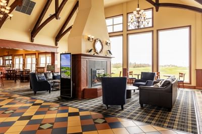Cozy lobby seating area by a large fireplace at the luxury accommodations of the PEI Rodd Crowbush Golf Resort