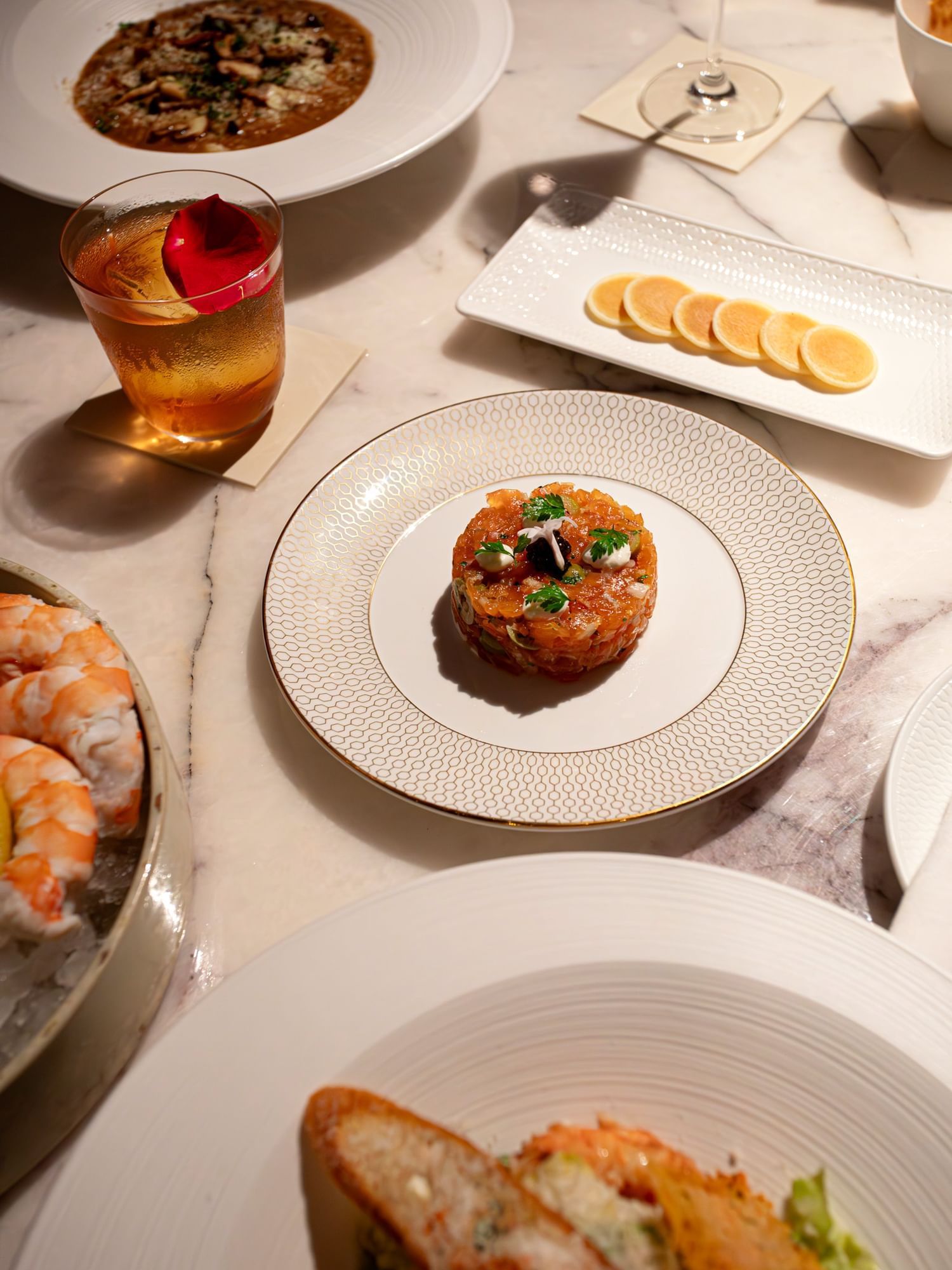A beautifully plated tartare dish surrounded by other gourmet food items served at The Londoner Hotel