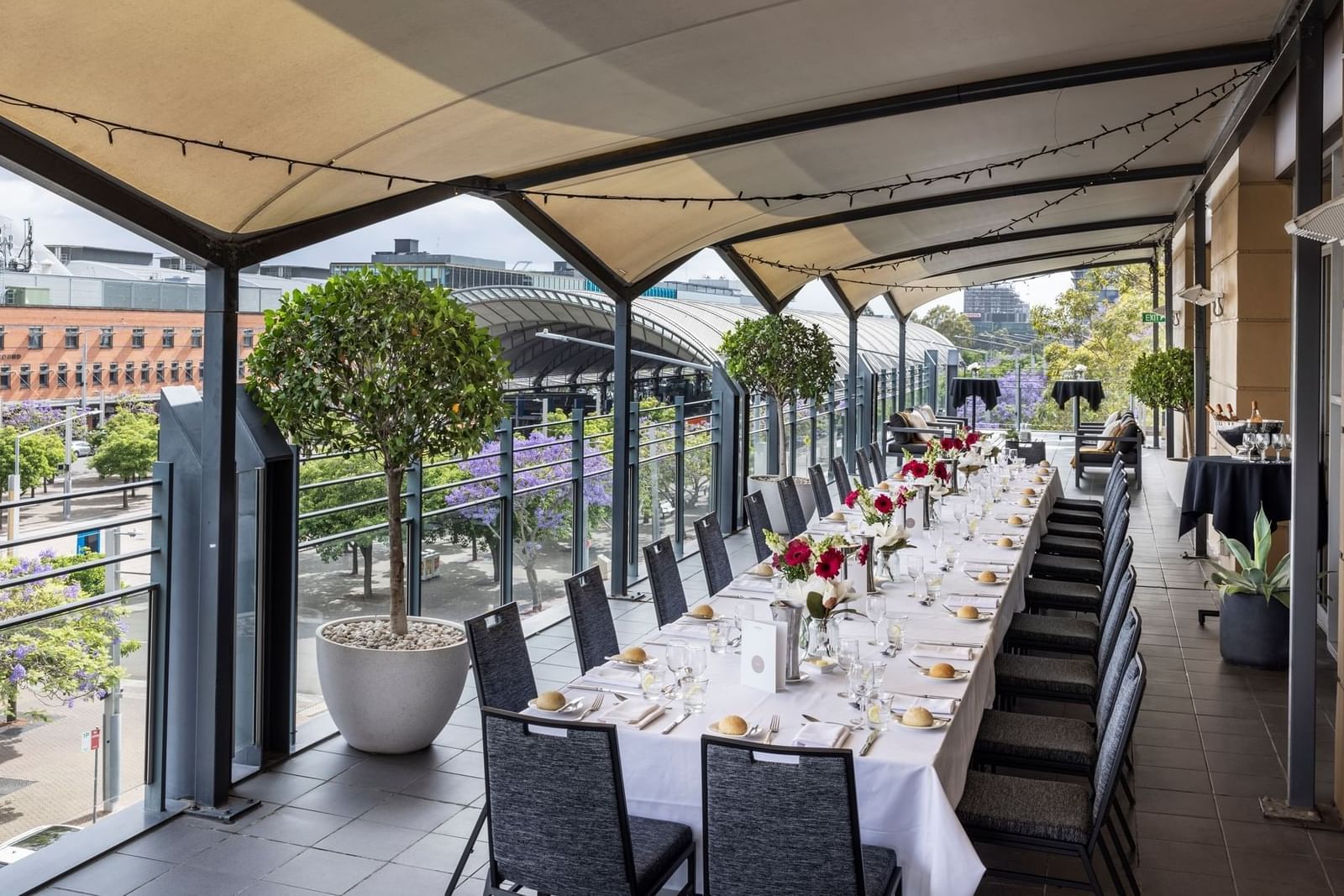 A elegantly set dining table on the Freshwater Balcony at Novotel Sydney Olympic Park, adorned with flowers & fine cutlery