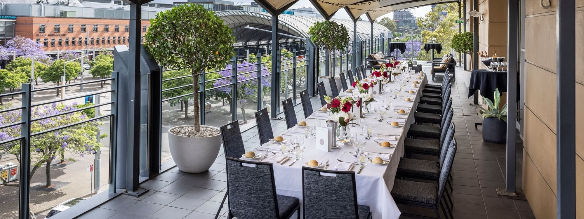 Beautifully set dining table with flowers on Freshwater Balcony, overlooking Accor Stadium at Novotel Sydney Olympic Park